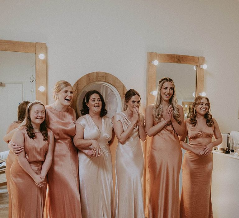 Bridesmaids in satin peachy coral dresses and satin pale champagne gold dresses 