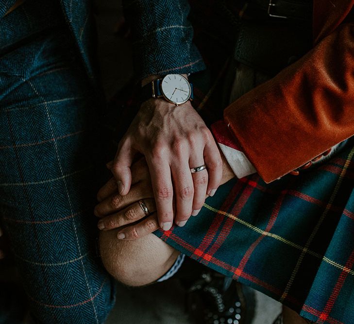 Groom places his hand across grooms hand wearing tartan kilt 