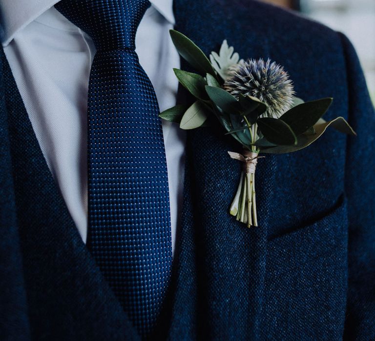 Thistle buttonhole worn by groom in a blue wedding suit 