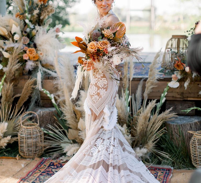 Bride in boho wedding dress with orange autumnal wedding bouquet with pampas grass