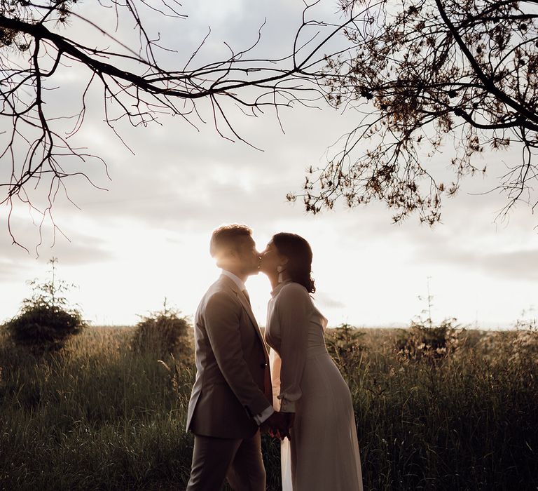 Bride and groom share a kiss as the sun starts to set 