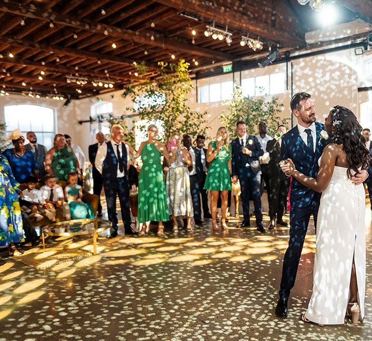 Bride & groom dance beneath disco ball on their wedding day as guests watch on during reception at Trinity Buoy Wharf 