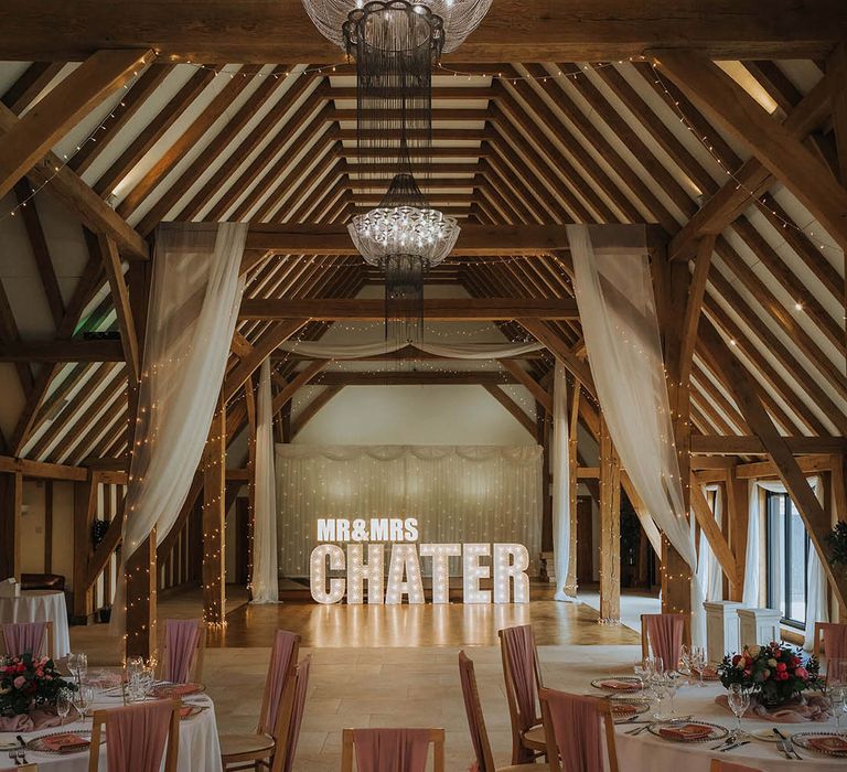 The Old Kent Barn wedding venue with drapes, fairy lights and light letters spelling out the couple's name 