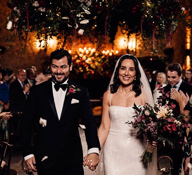 The wedding guests clap as the bride and groom exit the ceremony as a married couple