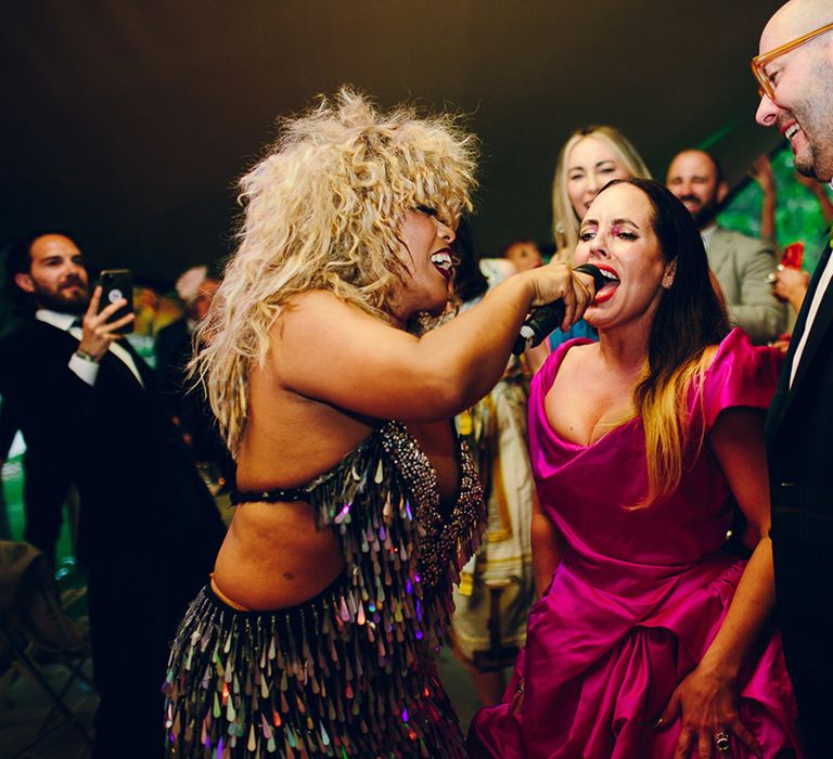 Wedding performer wearing open back detail sequin fringed party dress giving bride the mic for a sing-a-long