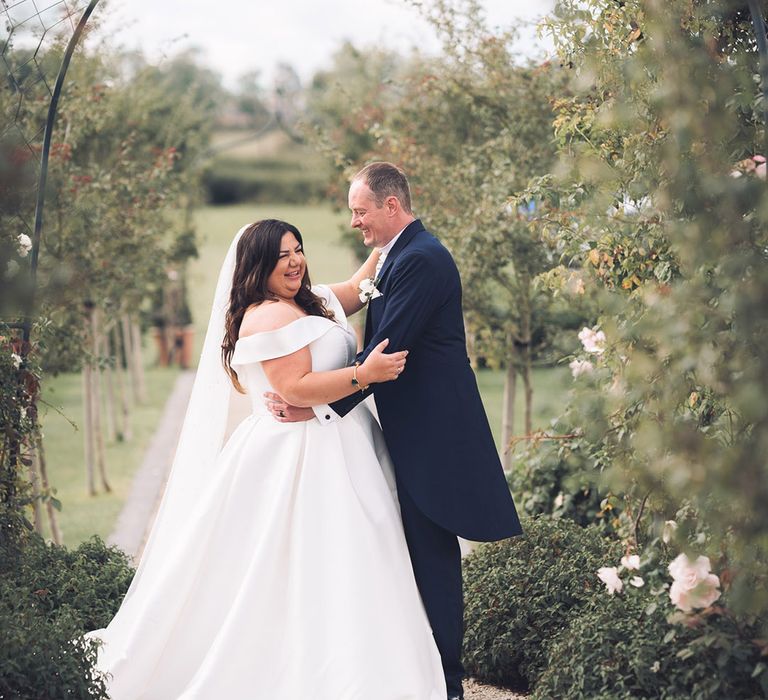 Bride in a pleated skirt wedding dress laughing with the groom for their couple portraits at Stratton Court Barn Bicester wedding venue 