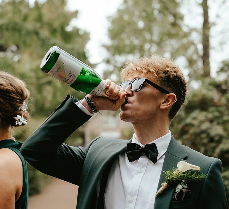 Groomsmen wears green suit with black bow-tie and white shirt, complete with white orchid buttonhole 