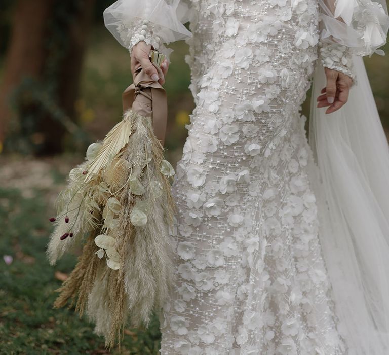 Bride wears appliqué Pronovias wedding dress whilst holding pampas grass bouquet 