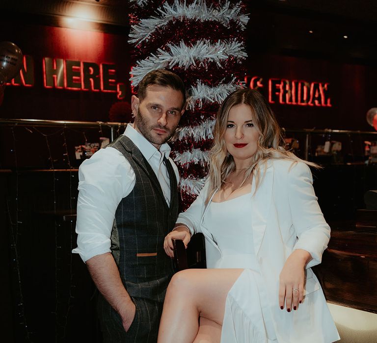 The bride sits on the bar at TGI Friday's with the groom standing next to her for festive Christmas celebrations after the wedding 