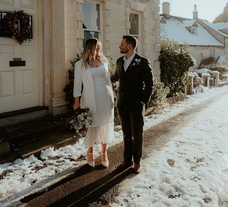 The bride and groom gaze lovingly at each other outside of Stroud Registry Office for their winter wedding 