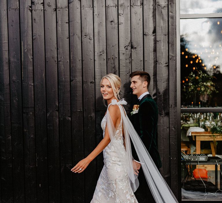 Bride in fitted lace Made With Love wedding dress with detachable tulle wings and bow straps with the groom in velvet tux for rustic barn wedding 