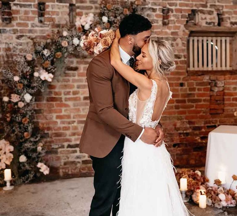 Bride and groom dancing surrounded by blush garden rose, dried flower and pink peony floral arrangements and pillar candles 