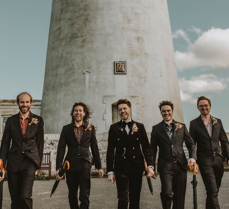 Groomsmen in black suits with mismatched patterned shirts with the groom in a velvet suit for North East lighthouse wedding 