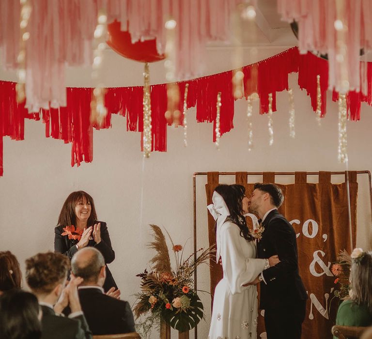 The bride and groom share their first kiss as a married couple at retro vintage wedding 