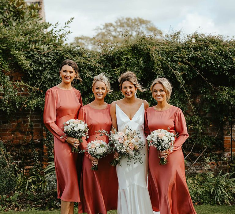 Bridesmaids in orange dresses with high neck and long sleeve details  