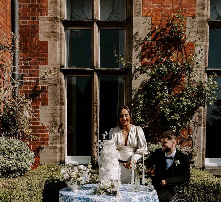 interabled couple cutting the wedding cake at Capesthorne Hall