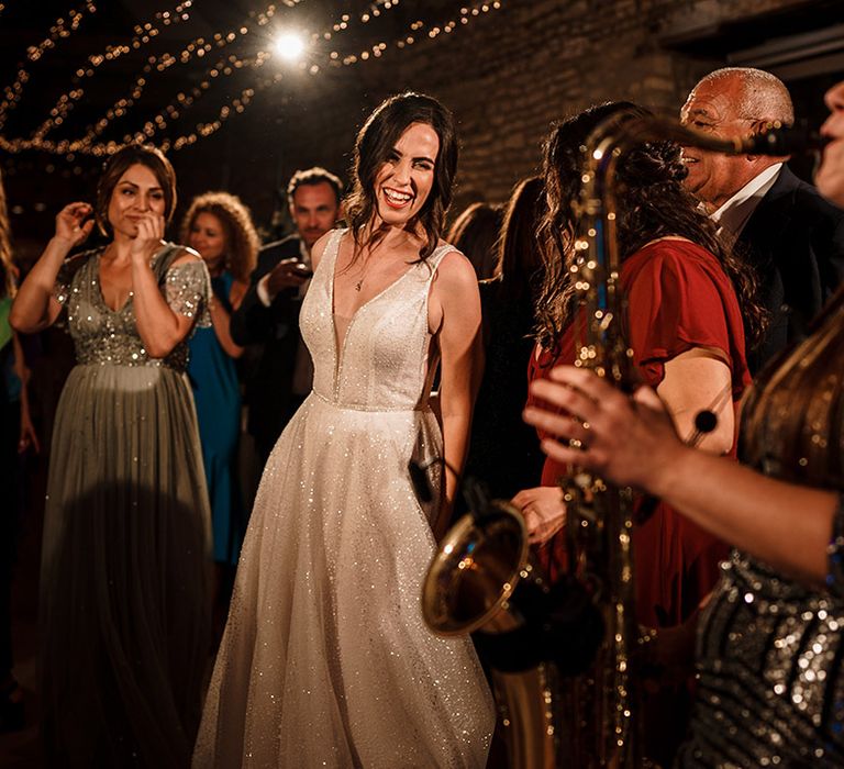 bride in a shimmering wedding dress at evening wedding reception with live saxophonist playing 