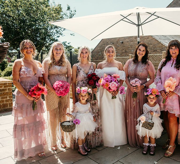 Bridesmaids in pink mismatched bridesmaid dresses holding pink wedding bouquets at tipi wedding 