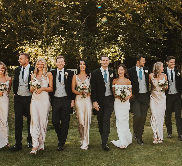 Glam wedding party with bridesmaids in gold satin cowl neck bridesmaid dress and groomsmen in morning suits 