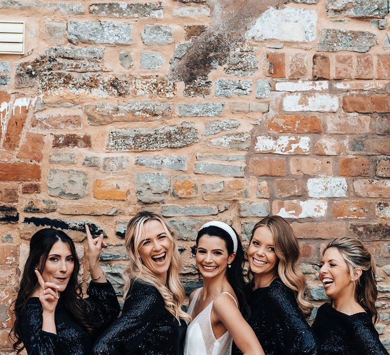 Bridal party in short black sequin sparkly dresses with long sleeves posing with the bride wearing a stylish headband accessory