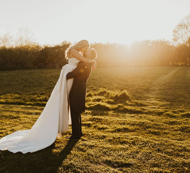 Golden hour wedding photos with the bride in a strapless Eva Lendel wedding dress with the groom in a black and grey morning suit 