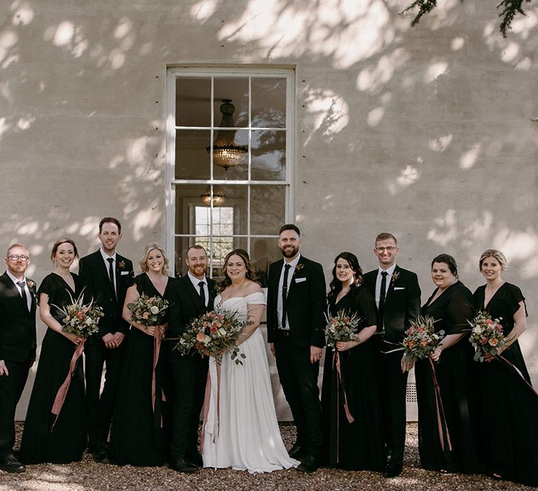 Black outfits for a minimalist chic wedding with bridesmaid in black bridesmaid dresses holding pink and white bouquets 