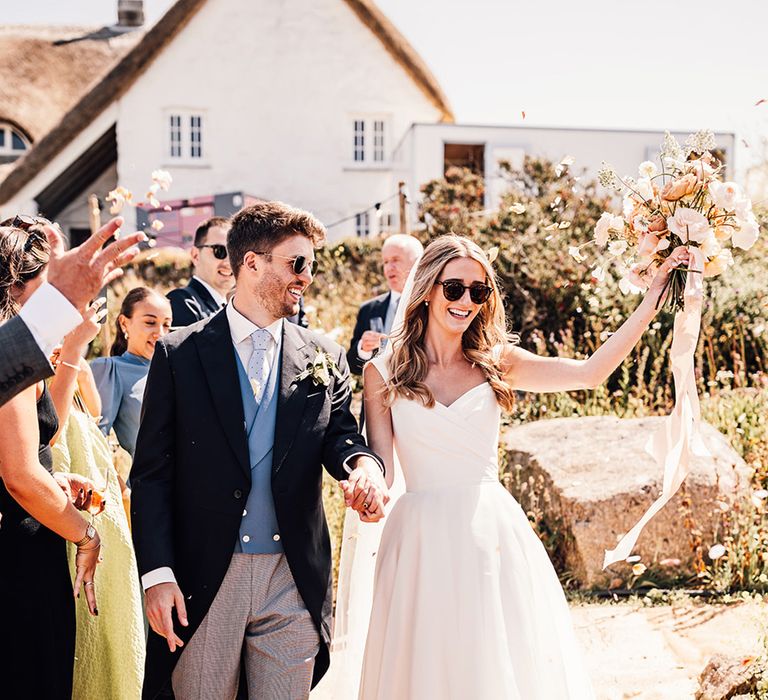 Sennen Cove wedding confetti moment with bride and groom wearing sunglasses 