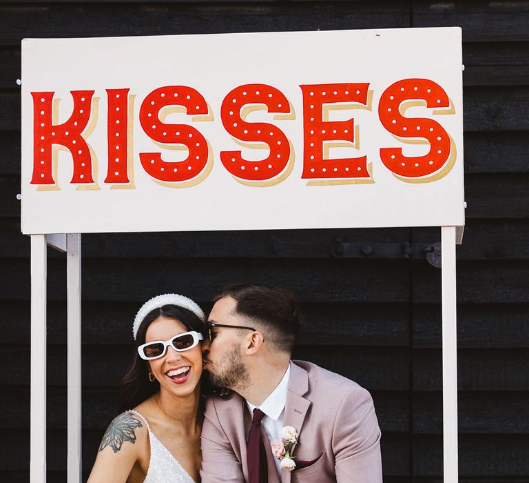 Kissing booth fairground game with bride and groom wearing wedding sunglasses 