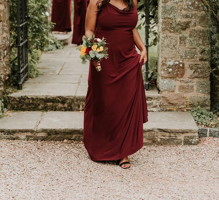 Bridesmaids wearing a burgundy red cowl neck bridesmaid dress for autumn wedding 