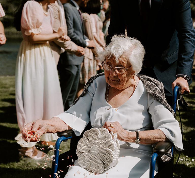 Grandma plays the role of the flower girl at the wedding with a pearl flower bag 