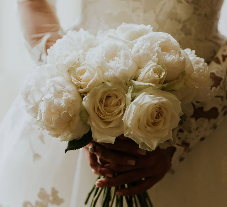 The bride holds a bouquet of white roses for the wedding 