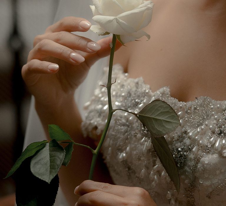 Bride with neutral wedding nails holding white rose 