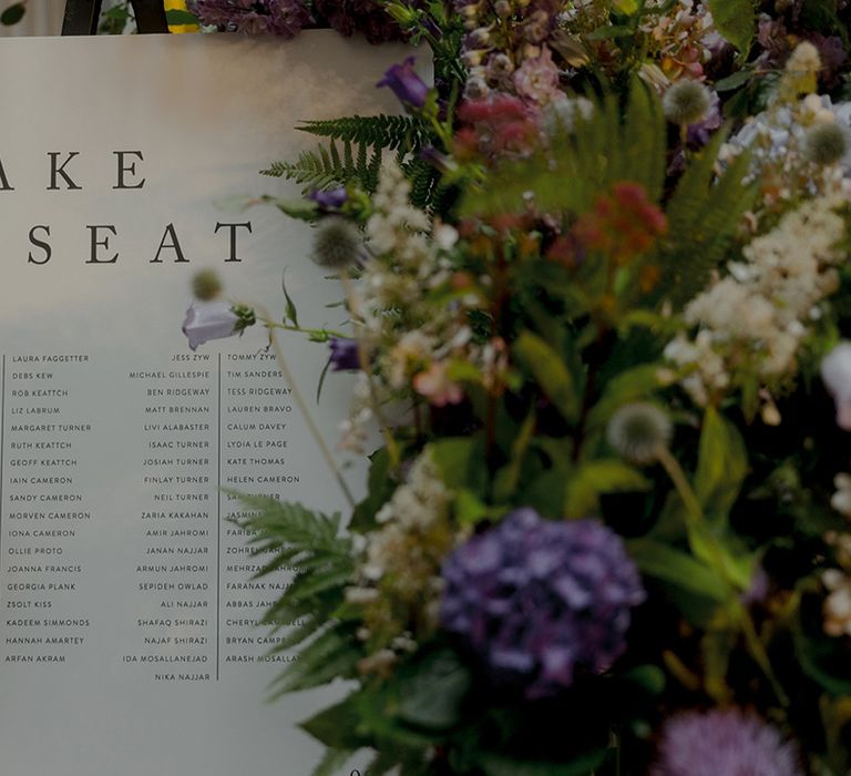 Wedding seating chart signage decorated with purple wedding flowers 