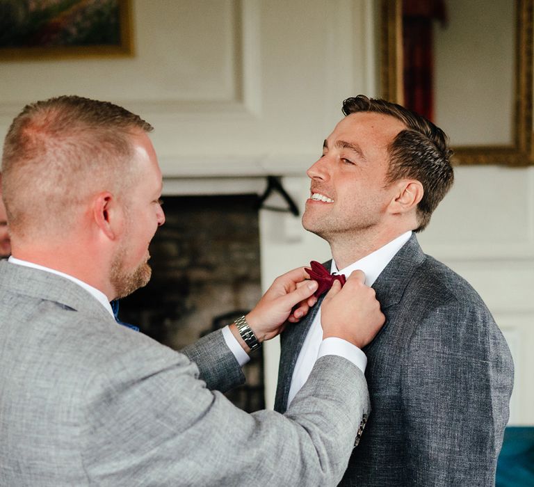 The groomsman helps the groom with a bow tie get ready for the wedding day 