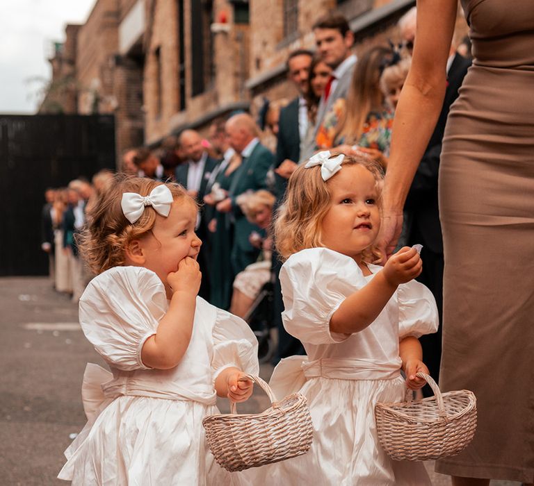 Flower girls in white dresses with hair bows at London wedding 