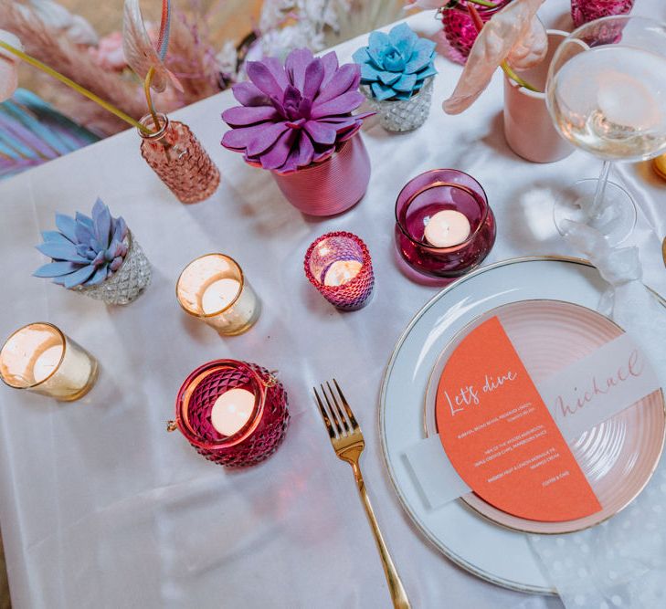 Place setting with colourful stationery and votives 