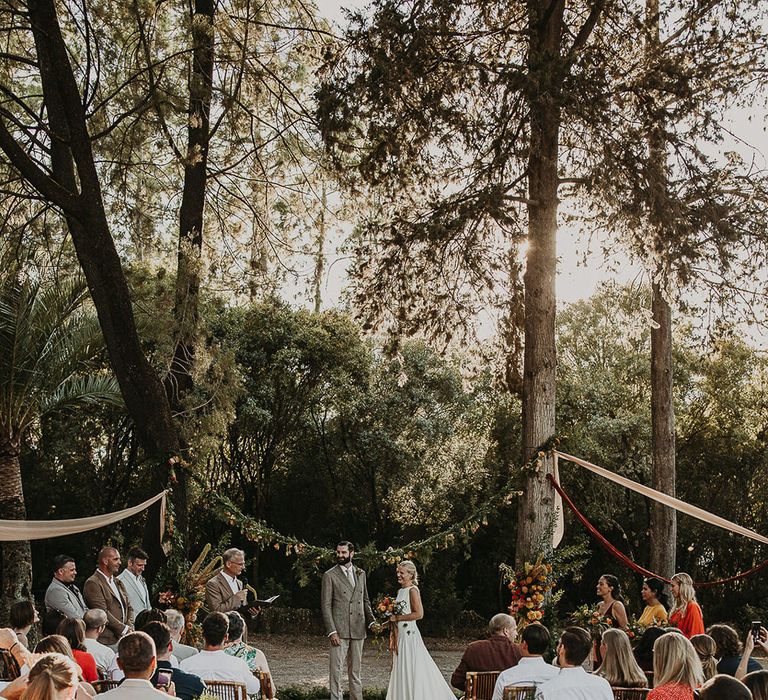 Forest wedding ceremony with wooden chairs and floral aisle flowers 