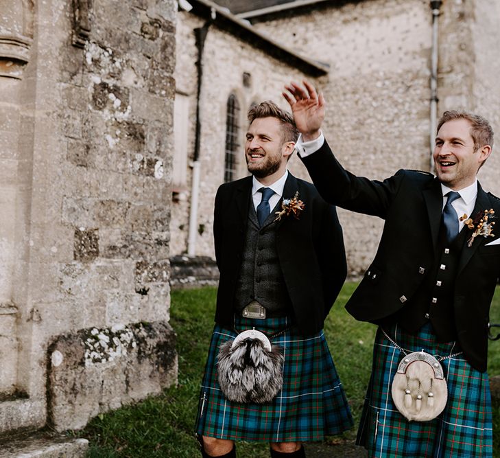 Groom and groomsmen wave to guests as they enter Christmas church wedding