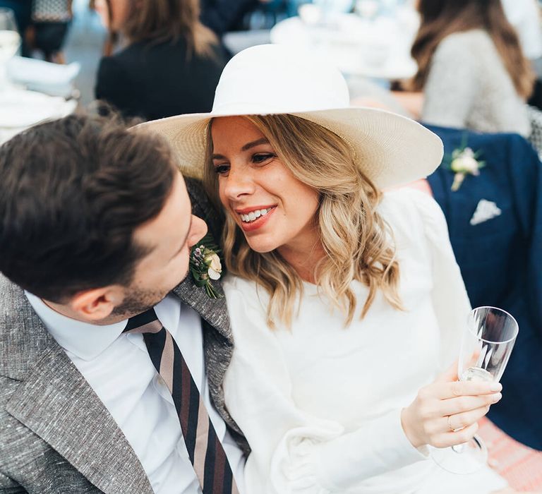 Bride sat on her new husbands lap smiling and drinking champagne 