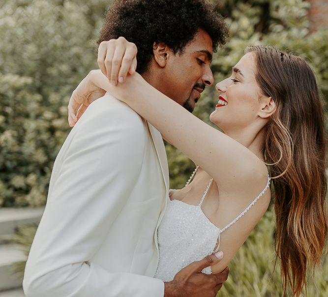 Black groom with afro hair about to kiss his bride with long brown hair and red lipstick 