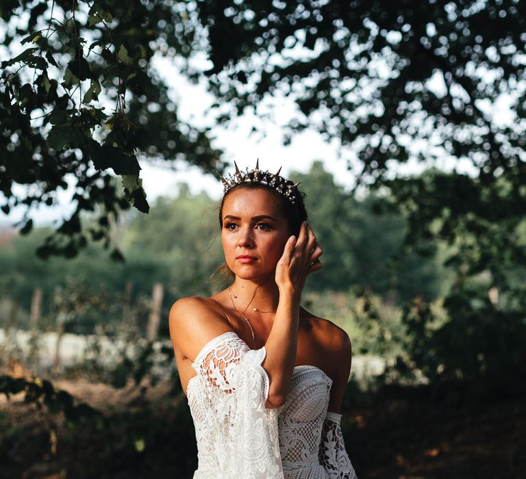 Bride stands in woodlands wearing lace gown