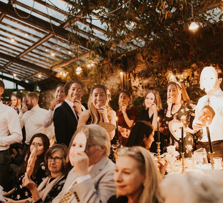 Wedding guests wearing face marks of the groom during the wedding reception 