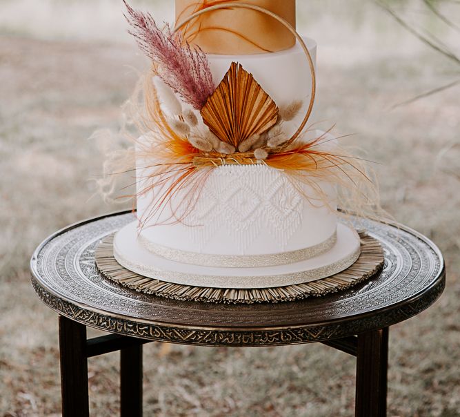 White & orange 4-tier cake with geometric macrame detailing 