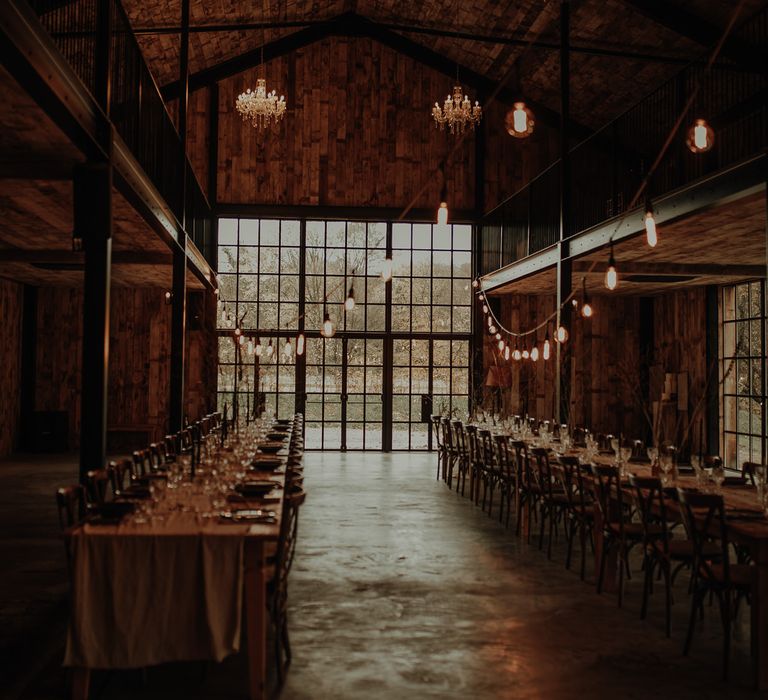 Banquet tables at Hidden River Cabins wedding venue with chandeliers hanging from the ceiling and festoon lights 