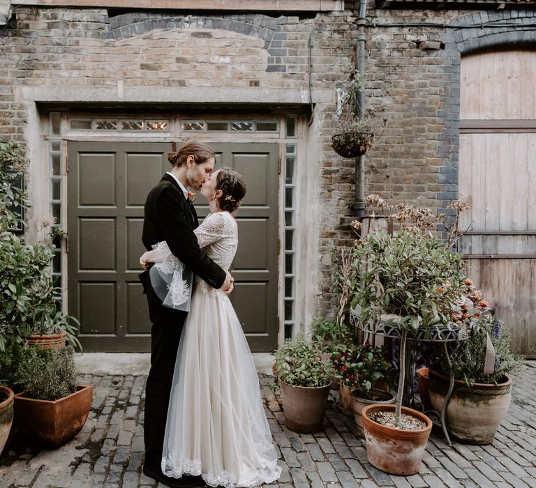 Bride and groom holding each other and kissing outside at winter wedding in London 