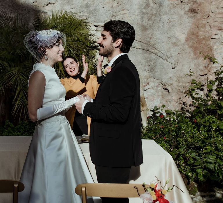 Celebrant clapping as the bride and groom hold hands and look into each others eyes, just married