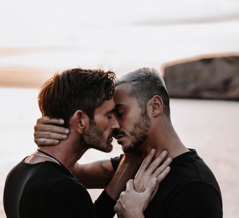 Grooms kiss during engagement session on the beach in Ibiza 