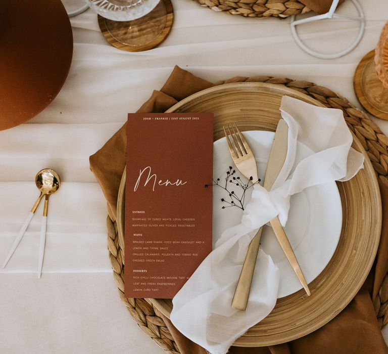 Neutral wedding tablescape with terracotta details, gold cutlery and white linen napkins