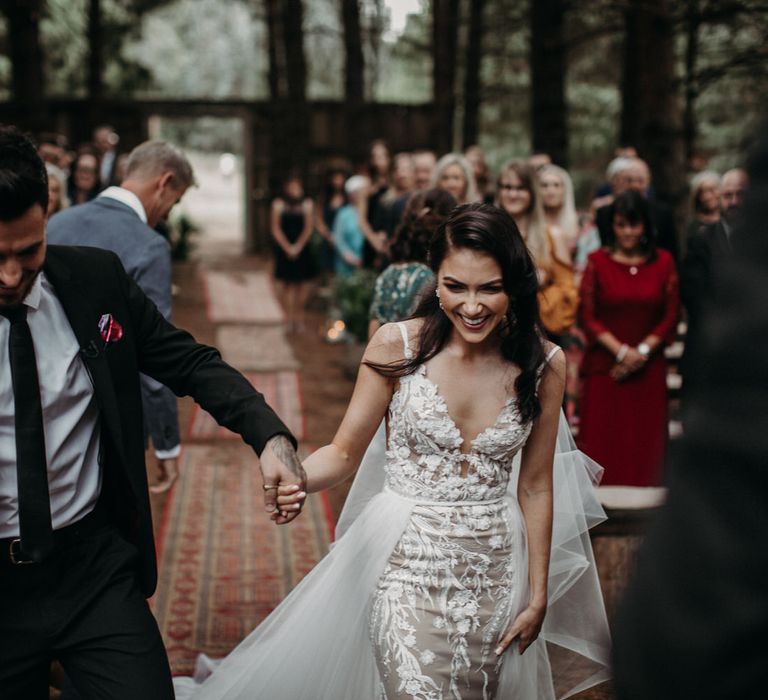 Bride and groom holding hands at their moody romantic wedding ceremony