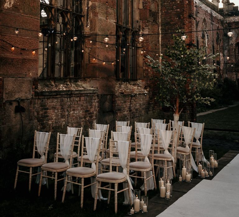 Outdoor wedding ceremony chairs with chiffon chair back decor and festoon lights 